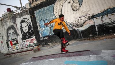 A Palestinian youth plays next to a graffiti showing Palestinian women held in Israeli jails during the International Women's Day in Gaza City. EPA