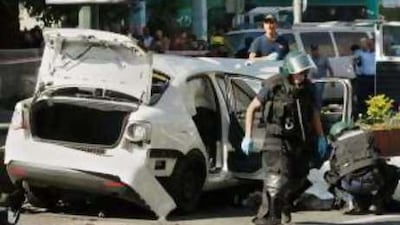 A police officer examines the body of a man, believed to be Mr Alperon, after the car bomb attack.