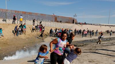 Maria Meza, a 40-year-old migrant woman from Honduras, part of a caravan of thousands from Central America trying to reach the United States, runs away from tear gas with her five-year-old twin daughters Saira Mejia Meza, left, and Cheili Mejia Meza, right, in front of the border wall between the US and Mexico, in Tijuana, Mexico, on November 25, 2018. Reuters