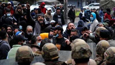 Protesters shout slogans in front of Lebanese soldiers in Tripoli. AP