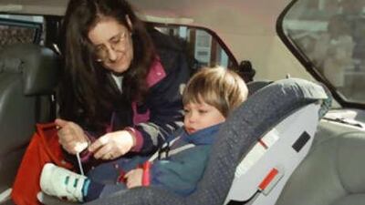 Susan Barocas, of Washington, buckles-up her son Samuel Phillips into his seat in the back of her car.
