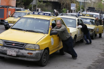 Taxi drivers push their cars to a petrol station in the Syrian capital, Damascus, after running out of fuel. Louai Beshara / AFP