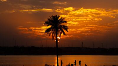 Iraqis stand on the shore of the Shatt al-Arab waterway, formed at the confluence of the Euphrates and Tigris rivers, as the sun sets over Iraq's southern city of Basra. AFP