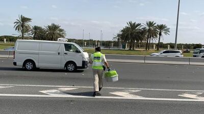 A policeman crosses Sheikh Zayed bin Sultan Street to save a cat stranded on the road barrier. Courtesy Simone Cutting