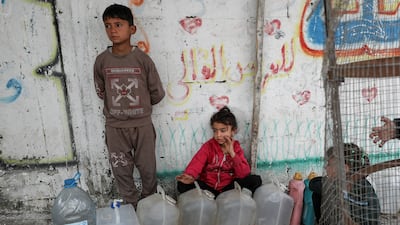 Palestinian children gather near containers used for water, in Gaza City. Reuters