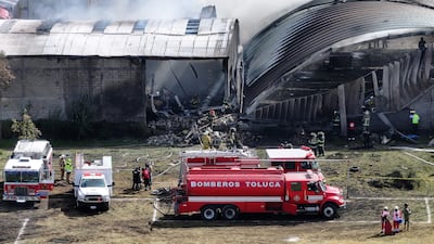 Firefighters extinguish a blaze caused by the crash of a Cessna Citation aircraft, which struck an industrial warehouse near Toluca International Airport, in Mexico. AFP