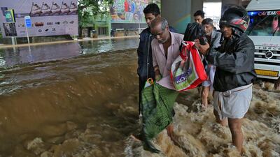 Rescue workers help people to cross a flooded road on the outskirts of Kochi. Reuters