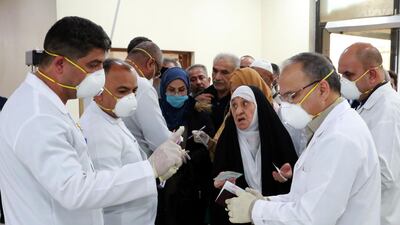 Members of Iraqi medical team check passengers upon arrival from Iran at Baghdad international airport on February 24, 2020. EPA