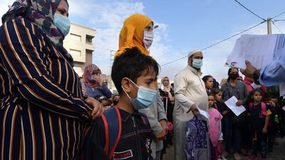 Tunisian pupils stand with their parents as they listen to announcement outside a primary school in the Ariane region near Tunis. AFP