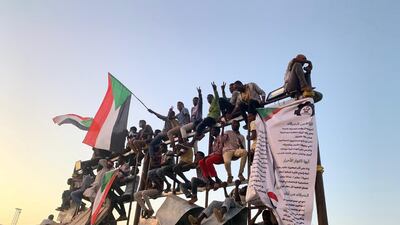 Protesters perched on a billboard frame at the sit-in outside the headquarters of Sudan's armed forces in Khartoum. Hamza Hendawi for The National