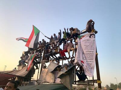 Protesters perched on a billboard frame at the sit-in outside the headquarters of Sudan's armed forces in Khartoum. Hamza Hendawi for The National