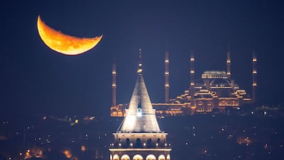 The crescent Moon rises behind Camlica Mosque and Galata Tower in Istanbul. AP
