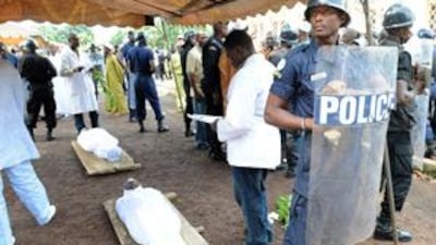 A policeman stands over the bodies of people killed by Guinean junta forces in Conakry.
