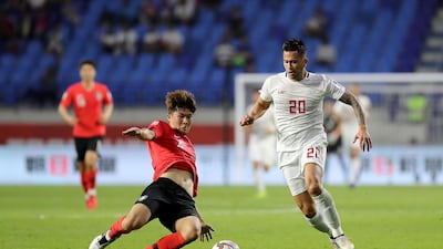 Kim Min-jae, in red, of South Korea challenges the Philippines' Javier Patino during their Asian Cup match.