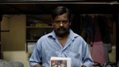 Babban Ram shows a photograph of his family in India, who have been struggling to get by because he has not been able to send them money.