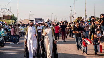Iraqi men dressed in traditional clothing walk together during an anti-government demonstration outside the local government headquarters in the southern city of Basra. AFP