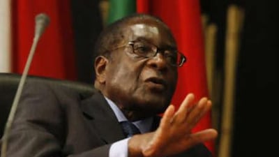 The Zimbabwean president, Robert Mugabe, speaks to aides during the summit of the Southern African Development Community in Johannesburg on Aug 17 2008.