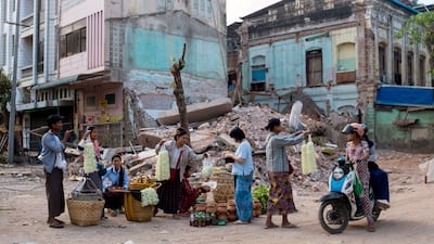 Flower sellers at work near a collapsed building in Mandalay on 12 April as Myanmar recovers from a 7.7 magnitude earthquake that killed more than 3,000 people two weeks ago. EPA