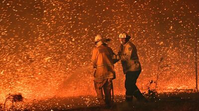 Firefighters struggling against the strong wind in an effort to secure nearby houses from bushfires near the town of Nowra in the Australian state of New South Wales. AFP