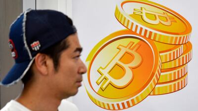 A pedestrian walks past a Bitcoin currency poster at the entrance of an electronics retailers store in central Tokyo. EPA/FRANCK ROBICHON