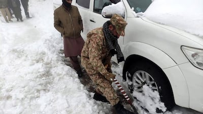 A soldier digs a car out of the snow. EPA