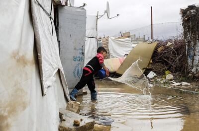 A Syrian refugee child empties water from a tent in Lebanon's Bekaa Valley after a storm last winter. AFP