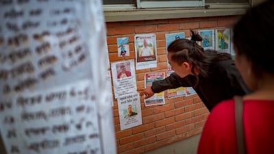 A man looks at photos of people reported missing, on a wall of Tribhuvan University Teaching Hospital.