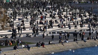 People sit on a bank of the Rhone River in Lyon, south-eastern France, before the start of a curfew. AFP