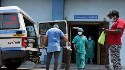 Health workers carry oxygen cylinders into a Covid-19 hospital in Kolkata on Saturday. A record 400,000 new daily cases were recorded in India on Saturday. EPA