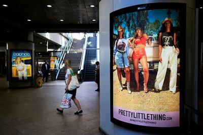 A shopper walks past advertising billboards for Boohoo and for Pretty Little Thing. Reuters