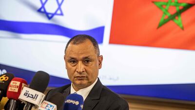 Ryad Mezzour addresses the media under the flags of Israel and Morocco. AFP