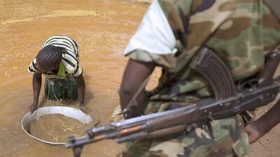 A former Seleka soldier looks at a woman washing extracted soil and small rocks as she pans for gold near an open-pit at the Ndassima gold mine near Djoubissi, north of Bambari. Siegfried Modola / Reuters