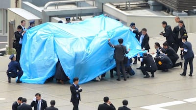 Police and security officers investigate an unidentified drone (under a blue cover) which was found on the rooftop of prime minister Shinzo Abe’s official residence in Tokyo, in this photo taken on April 22. Reuters
