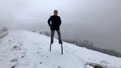 Sabah Abdelrahman, a municipality employee, walks through a snow-covered road using stilts made out of tree branches, in Akra, Iraq, January 20, 2021. Picture taken January 20, 2021. REUTERS/Kawa Omar NO RESALES. NO ARCHIVES