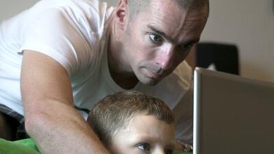 Jamie French gets a little help from his father Neil French as he reads one of a series of e-books designed to help children improve their literacy. Silvia Razgova /The National