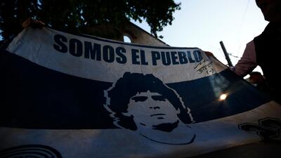Fans show a flag with the face of Diego Maradona at Clínica Olivos. Getty Images