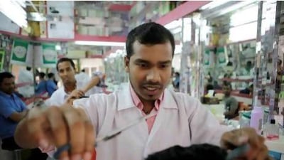 Dipik Sill, a barber at the Sunlight Men’s Salon, cuts a cusotmer’s hair yesterday afternoon in Abu Dhabi. Workers in salons will have to pass an exam after professional training courses.