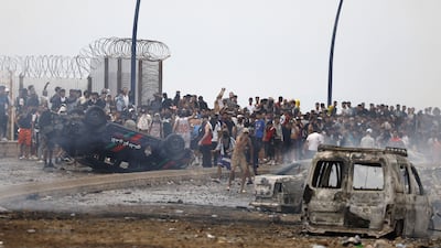 People gather next to an overturned police vehicle at the site of clashes near Fnideq, on the Morocco-Spain border. AFP
