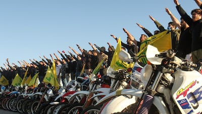 Hezbollah supporters perform a salute as they stand behind motorcycles carrying the group's flags in the southern Lebanese district of Marjayoun on the border with Israel on May 25, 2020. AFP
