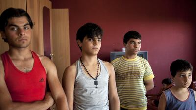 Young men who fled Syria from Idlib pose for a portrait inside the home they share with three families.