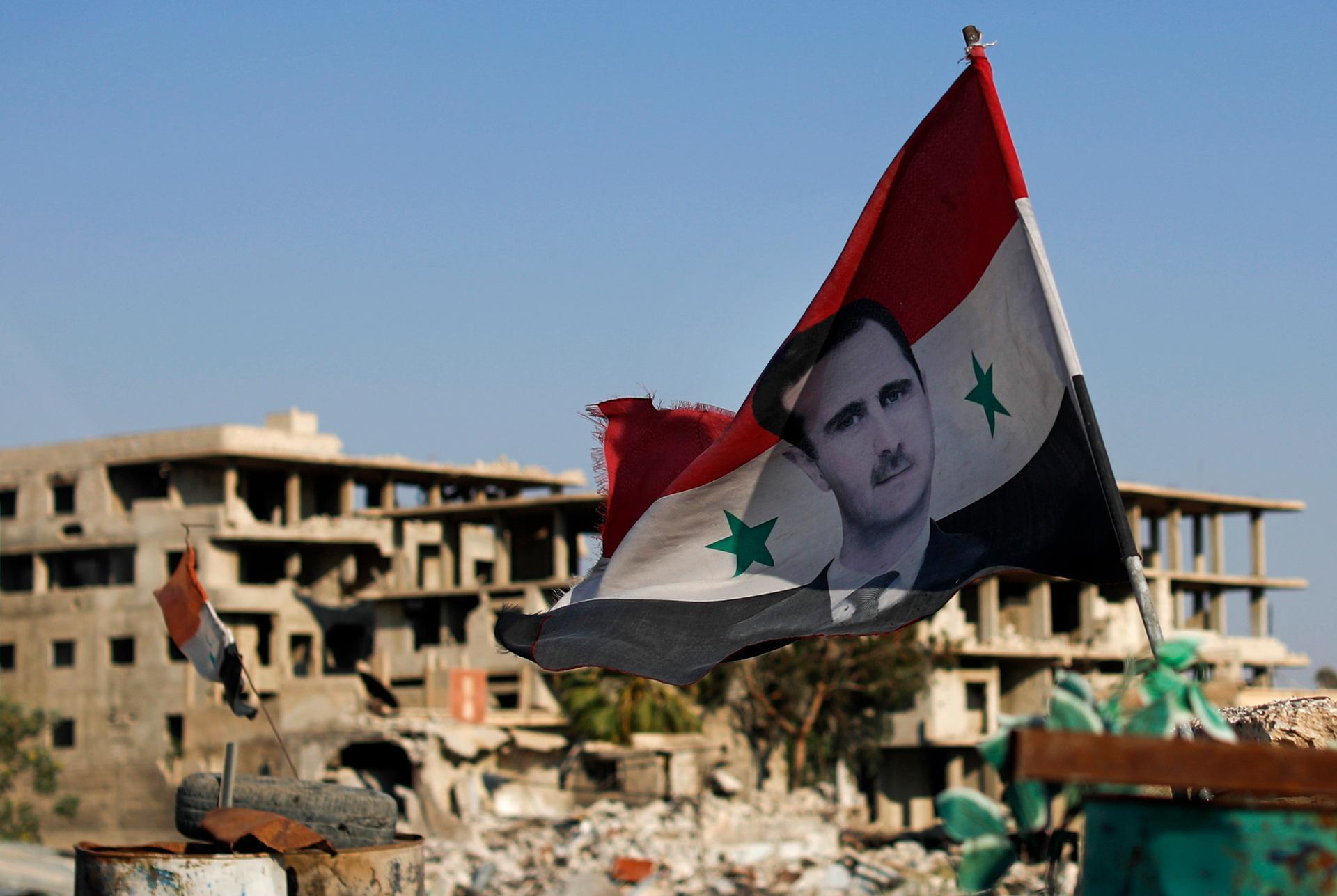 A Syrian flag with a picture of Bashar Al Assad flies in the town of Douma near Damascus on July 15, 2018. AP Photo