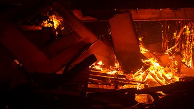 Flames still burn within the rubble of a house destroyed by the coastal fire in Laguna Niguel. EPA