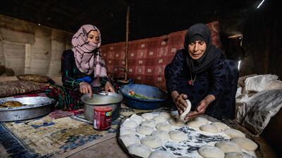 Two Syrian women prepare food at the Kabsh camp for displaced people in the countryside near Syria's northern city of Raqa during the Muslim holy month of Ramadan on April 7, 2022. (Photo by Delil souleiman / AFP)