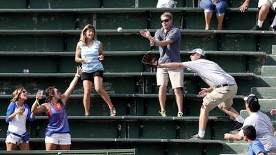 In this September 4, 2013 file photo, baseball fans in Wrigley Field's left field bleachers scramble for a batted ball during a Chicago Cubs baseball game in Chicago. Wrigley was the first ballpark where fans could keep foul balls. The first permanent concession stands? They were at Wrigley. The first stadium with organ music? That was Wrigley, too. Charles Rex Arbogast / AP