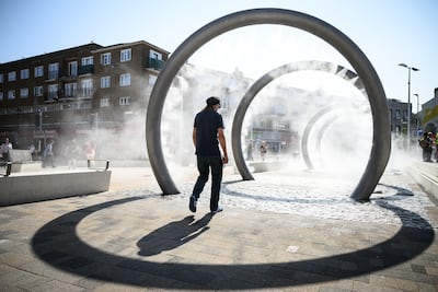 A person walks through an art installation in Dover, as it sprays a cloud of cool water vapour. Getty Images