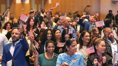 People wave flags at a naturalisation ceremony at the John F Kennedy Library and Museum in Boston. The Boston Globe / Getty Images