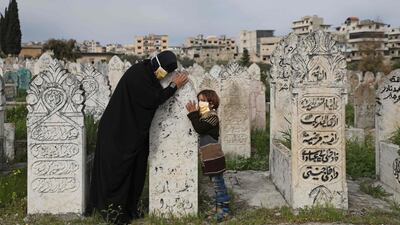 A displaced Syrian woman and her daughter visits a grave of a relative in the town of Ariha in the northern countryside of Syria's Idlib province on April 5, 2020. AFP