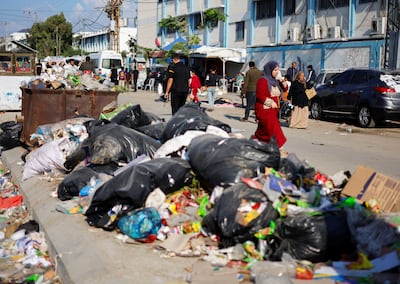 Palestinians walk past piles of rubbish that threaten to spark an environmental catastrophe, Reuters