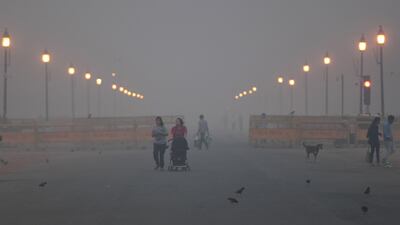 Indian pedestrians walk near the India Gate monumnet amid heavy smog conditions in New Delhi. AFP