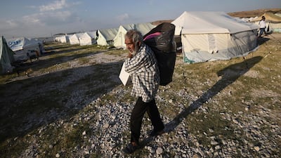A migrant carries his belongings at a refugee camp in Nea Kavala, northern Greece. About 1,500 asylum-seekers transported from Greece's eastern Aegean island of Lesbos to the mainland. Around 1,000 of those transferred and housed in Nea Kavala, where they will be staying in tents until the end of the month, after which they will be transferred to a new camp under construction. AP